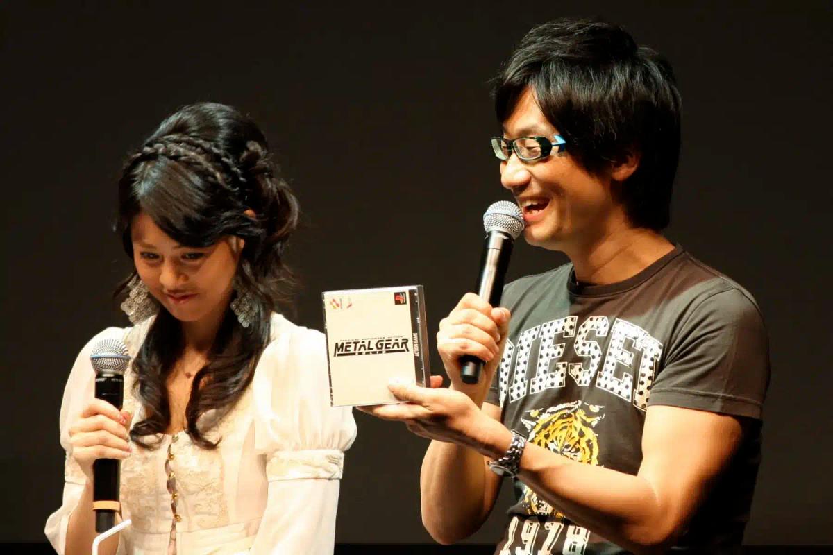 Hideo Kojima يمسك بغلاف لعبة Metal Gear ويتحدث في ميكروفون.